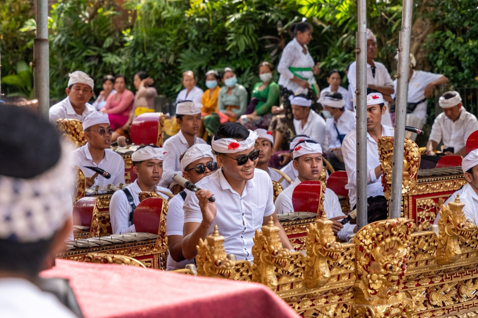Balinese gamelan musicians playing outdoors in traditional dress.