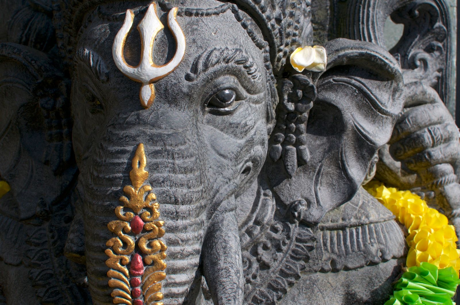 A carved stone Ganesha statue with flower offerings, Ubud, Bali.